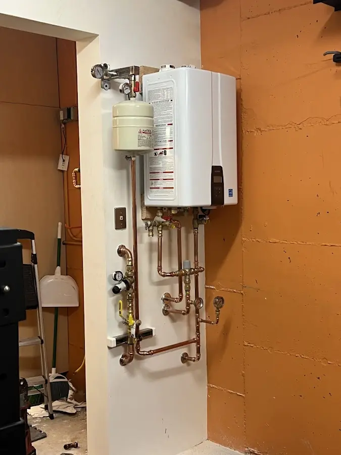Plumbing technician inspecting water heater connections in Evans